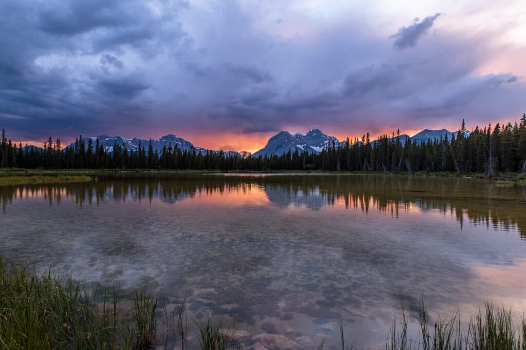 The sun sets over a pond in Spray Valley Provincal Park in Alberta, Canada.